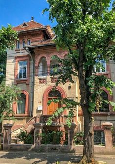 an old building with many windows and balconies on the second floor is surrounded by trees