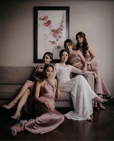 a group of women sitting on top of a couch in front of a framed painting