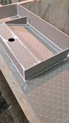 a metal tray sitting on top of a piece of plywood in a building under construction