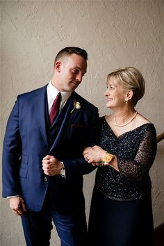 a man in a blue suit and woman in a black dress standing next to each other