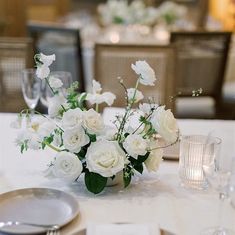 a table with white flowers and silverware on it