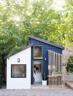 a small blue and white shed with plants in it