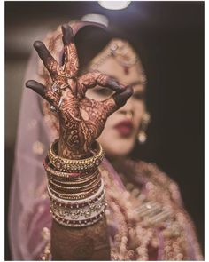 a woman holding up her hands with henna on it's fingers and wearing jewelry