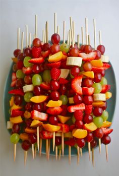 a bunch of fruit is stacked on top of each other with toothpicks sticking out of them