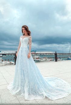 a woman in a blue wedding dress standing on the ground with her hand on her hip