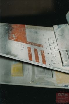 a close up of a metal object with some writing on the side and an orange stripe in the middle