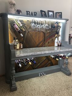 a bar with wine glasses and bottles on it's back wall in a living room