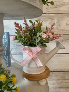 a watering can filled with flowers on top of a table