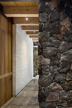 an open door leading to a stone wall and wooden floored area with wood paneling