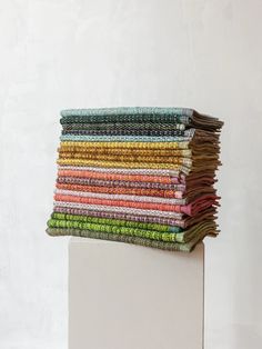 a stack of folded papers sitting on top of a white pedestal in front of a wall