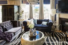 a living room filled with furniture and a chandelier hanging from the ceiling over a fire place