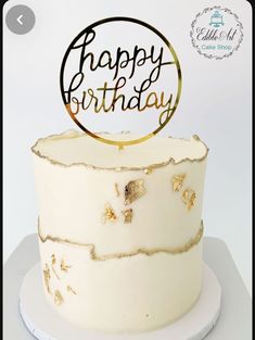 a white and gold birthday cake with the words happy birthday on it's top