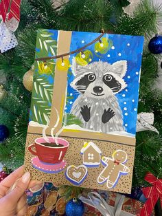 a painting of a raccoon is hanging from a christmas tree with decorations around it