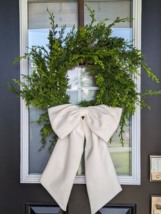 a wreath on the front door with a bow hanging from it's side window