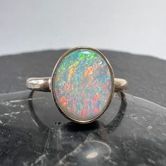 Exceptional Australian opal 14k gold statement ring with nice size oval stone from the Coober Pedy field. Currently US size 7 3/4 (select size at checkout) Australian Opal - 1.38 carats, 10.83mm x 8.75mm x 2.41mm One of kind, hand made. All of our creations are made out of 14K Gold (Yellow, White, Rose) or 925 Sterling Silver, None are filled or electroplated.  All of our stones are Nature-made, therefore some natural flaws may be present. Hand crafted in the We Work Gems Shop in Washington State. Size and weight are approximate. Please feel free to ask any questions. Back to our shop https://www.etsy.com/shop/weworkgems 24D12 Oval Opal Rings With Polished Finish, Classic Ethiopian Opal Ring In Oval Shape, Elegant Untreated Oval Opal Ring, Elegant Oval Untreated Opal Ring, Oval Cabochon Opal Ring With Polished Finish, Polished Opal Oval Cabochon Ring, Polished Opal Ring In Oval Cabochon Shape, Oval Opal Cabochon Ring, Opal Oval Cabochon Ring With Polished Finish