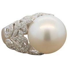 A luminous 15.5mm-16mm South Sea pearl surrounded by 0.75 carats of VS quality diamonds. The colorless round cut diamonds are set in a lavish 18K white gold filigree ring with a milgrain design. Ring Size 6.75 (Sizable) White Pearl Rings With Brilliant Cut, Formal Diamond White Pearl Ring With Diamond Accents, Classic Pearl White Diamond Ring, Exquisite White Pearl Ring With Diamond Accents, Luxury Diamond White Pearl Ring For Formal Occasions, Pearl White Diamond Pearl Ring With Diamond Accents, Pearl White Pearl Ring With Diamond Accents, Pearl White Diamond Pearl Ring With Accents, Formal Diamond White Pearl Ring With Center Stone