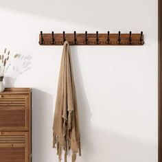 a coat rack with two coats hanging on it and a towel next to it in front of a dresser