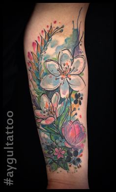 a tattoo with flowers and leaves on the arm, done in watercolor pencils