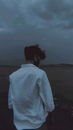 a man standing on top of a beach under a cloudy sky