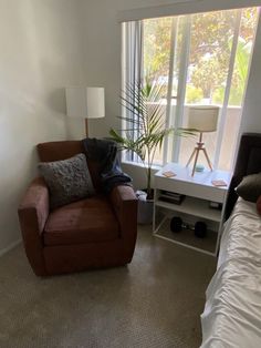 a living room with a couch, chair and lamp next to a window in the corner