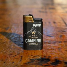 a lighter sitting on top of a wooden table next to a bottle of camping liquid