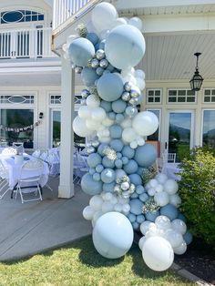 a tall blue and white balloon sculpture in front of a house with tables set up outside