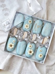 a box filled with blue and white cookies covered in frosting next to a tag