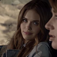 two young women sitting in the back seat of a car looking at something off to the side