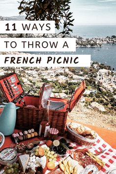 a picnic table with bread, cheeses and wine on it in front of the ocean