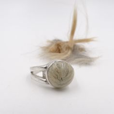 a close up of a ring on a white surface with feathers in the foreground