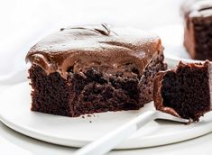 a piece of chocolate cake on a white plate with a bite taken out of it