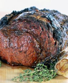 a large piece of meat sitting on top of a wooden cutting board next to garlic