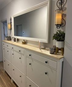 a large white dresser sitting next to a mirror on top of a wooden countertop