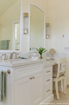 a white bathroom with two sinks and mirrors