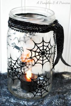 a glass jar filled with candles and spider webs