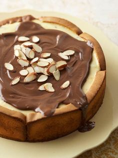 a cake with chocolate frosting and almonds on top sitting on a white plate