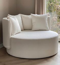 a white round couch sitting in front of a window