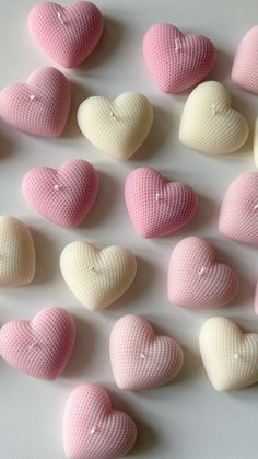 many pink and white heart shaped candies are arranged in a row on a table