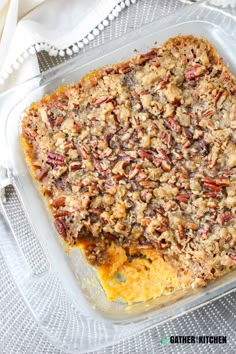 a casserole dish filled with sweet potato casserole topped with pecans