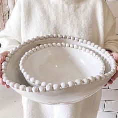 a person holding a white bowl with beads on the bottom and in between their hands