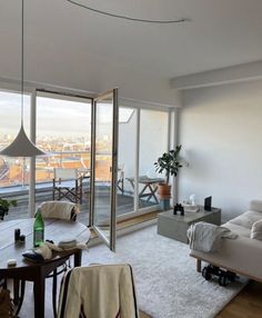 a living room filled with furniture and a large window overlooking the cityscape in the distance