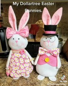 two stuffed bunnies dressed in pink and white outfits standing next to each other on a counter