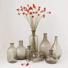 several glass vases with red flowers in them