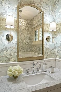 a bathroom sink sitting under a large mirror next to a light on the side of a wall