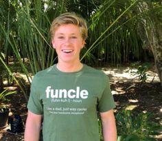 a young man is standing in front of some palm trees and smiling at the camera