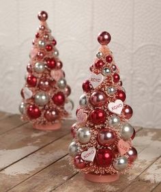 a red and silver christmas tree with hearts on it's top, sitting on a wooden table