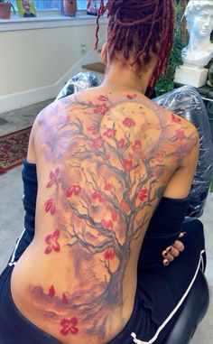 a woman with tattoos on her back sitting down