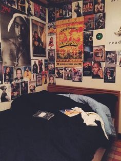 a bed room with a neatly made bed and many posters on the wall above it