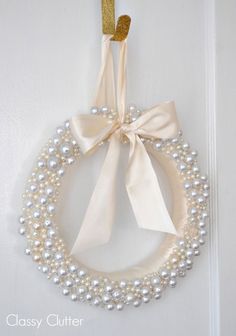 a wreath with pearls and a bow hanging on the door