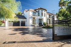 a large white house sitting on top of a lush green field next to a gate